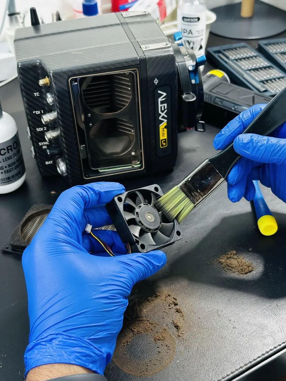Technician inspecting a cinema camera cooling fan at the service bench