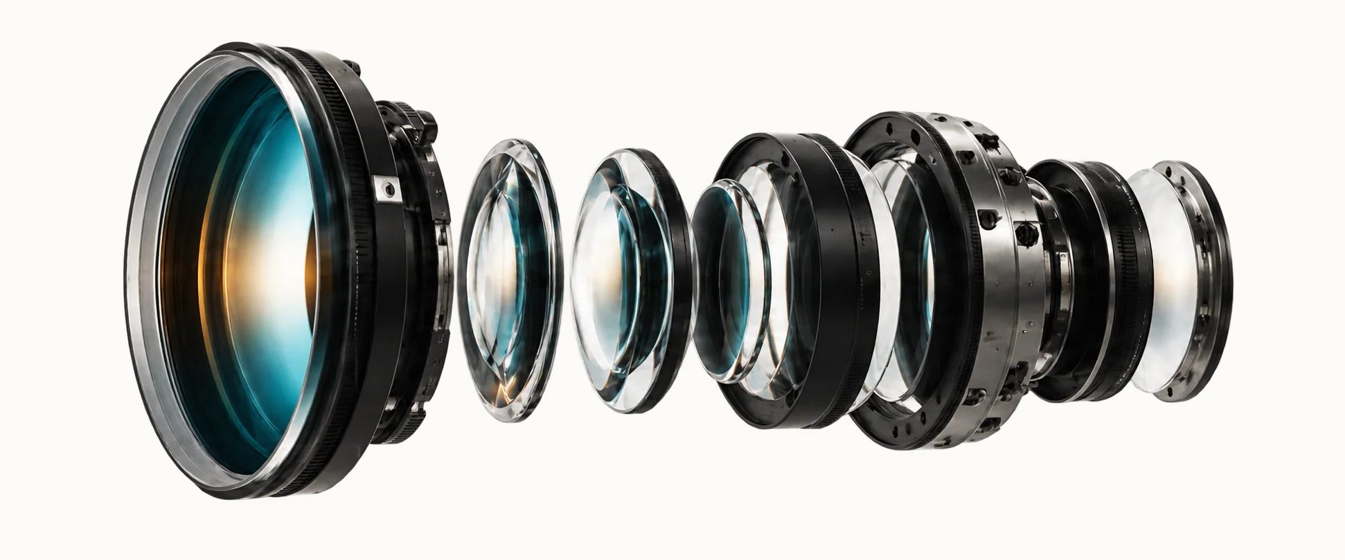 Exploded cinema lens assembly showing the optical elements serviced by OptiServ